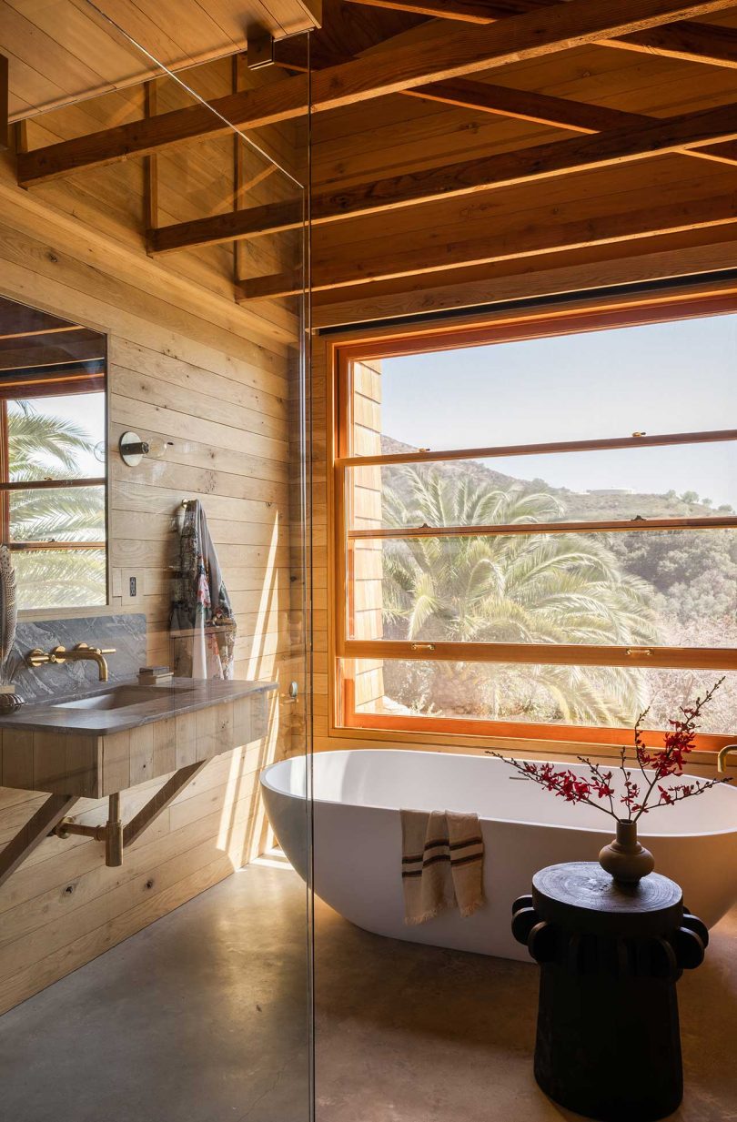primary bathroom of modern mountain house with wood details and white tub