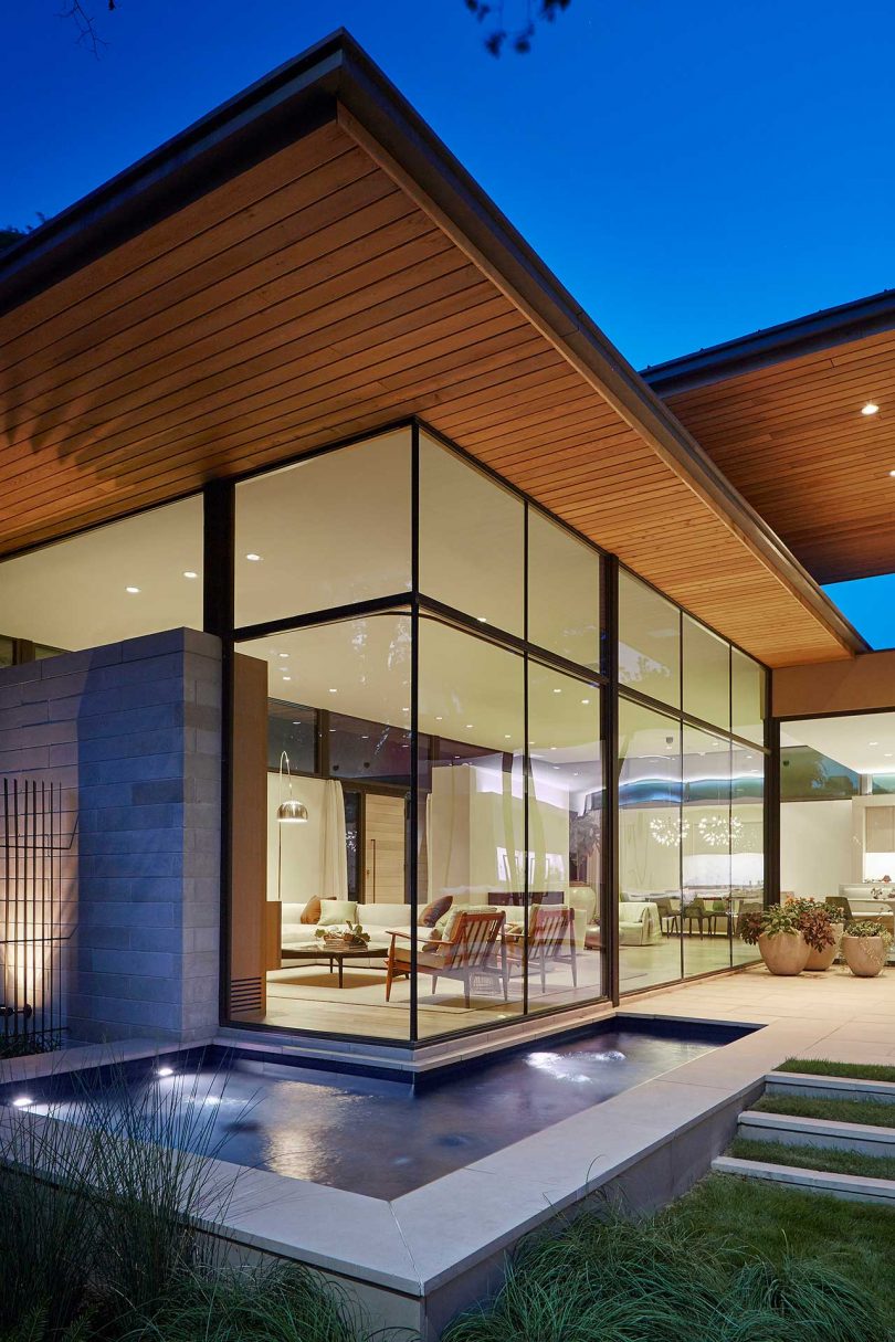 exterior view at twilight of modern home with glass walls and water feature