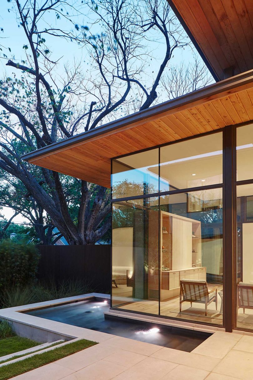 exterior view at twilight of modern home with glass walls and water feature