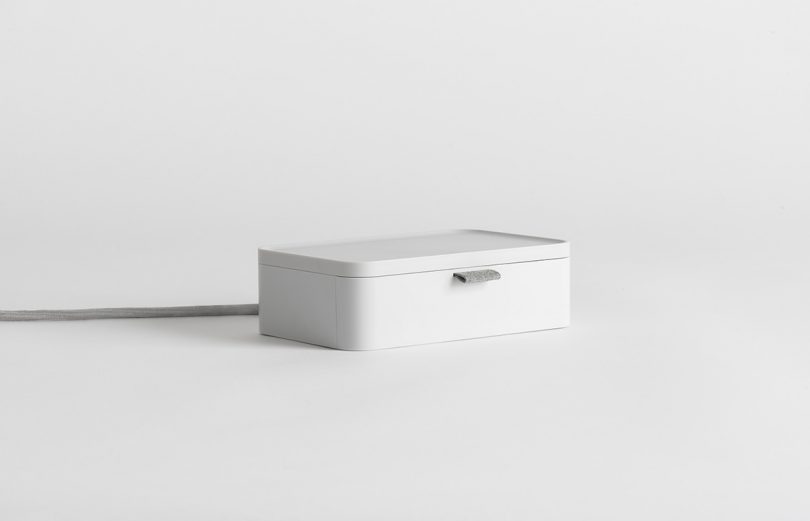 Closed Ampli charging station in white against white background.
