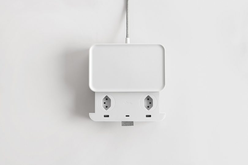 Overhead of opened Ampli charging station showing USV ports and two outlets, in white against white background.