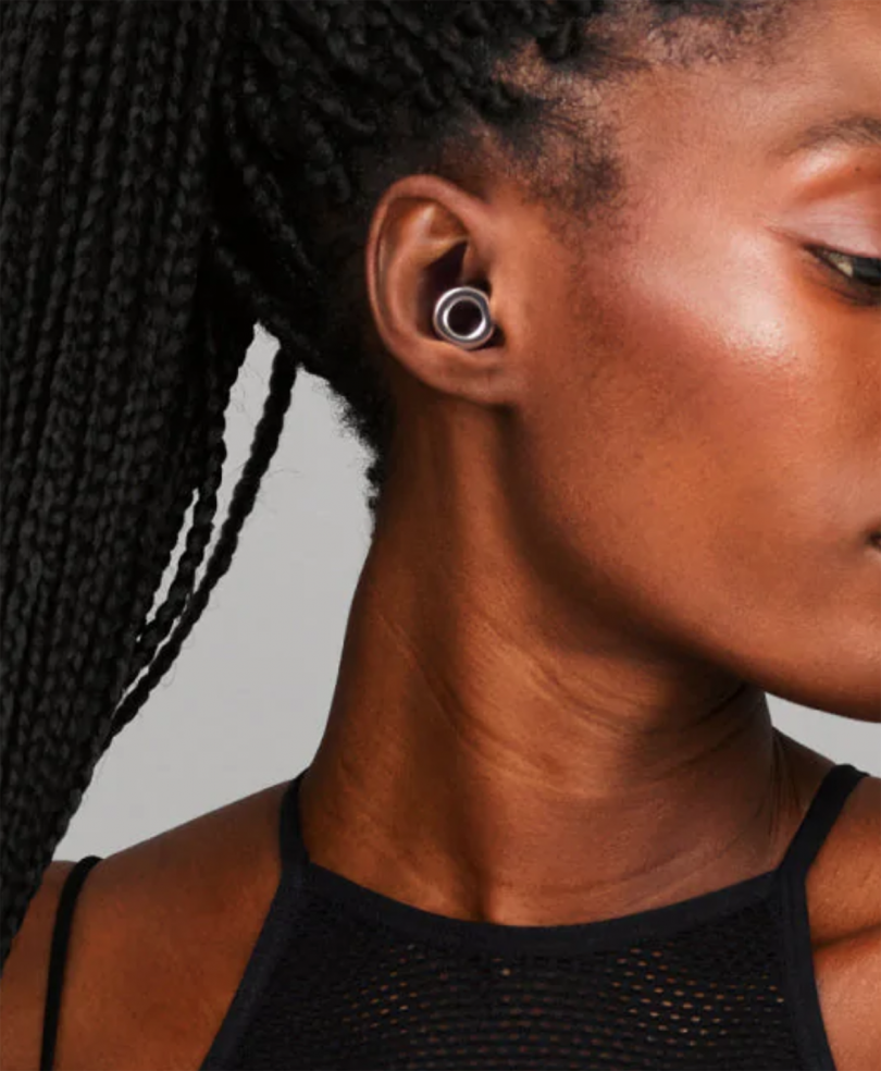profile of dark-skinned woman with pulled back braids wearing small looped earplugs