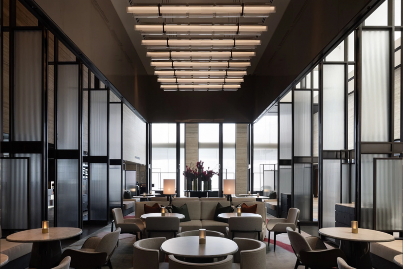 high design hotel lobby in moody tones wit round tables and armchairs