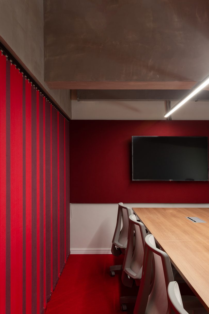 meeting space with conference table, chairs, a screen, and dark red privacy curtain