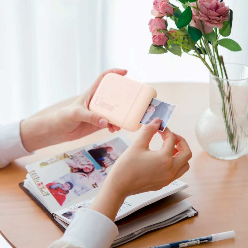 hands holding small portable printer at table