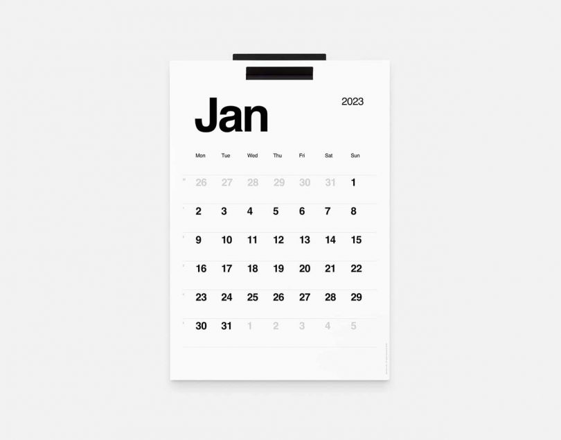 minimalist black and white calendar hanging on black wall bracket
