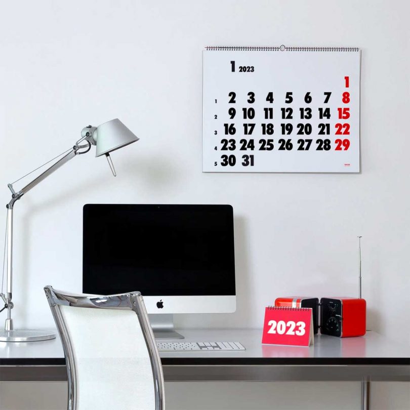 white, black, and red wall calendar hanging on wall above desk