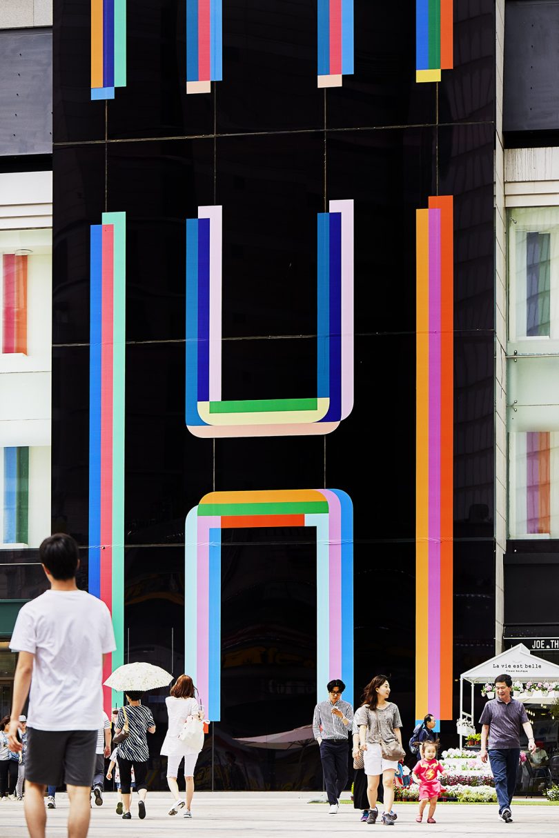 building exterior in black and bright colored geometric lines with people passing by