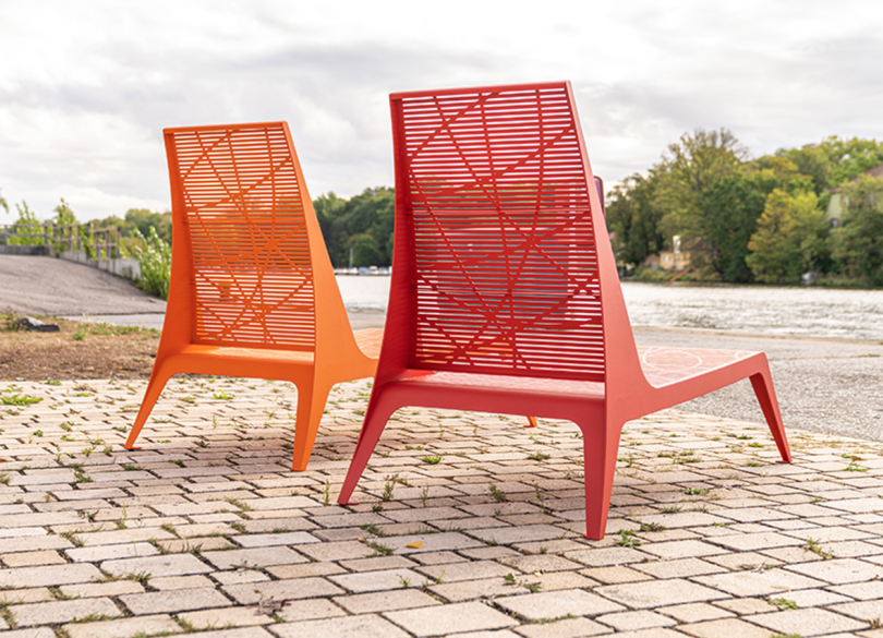 two orange and red low outdoor chairs on a brick surface