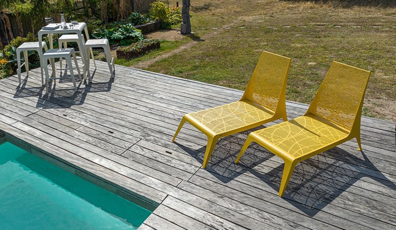 two yellow low outdoor chairs on a wood pool deck