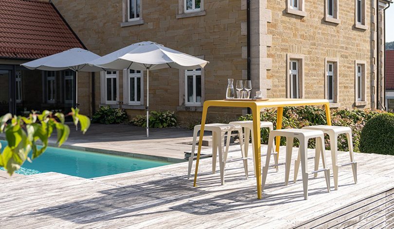 outdoor dining table and stools on a wood pool deck