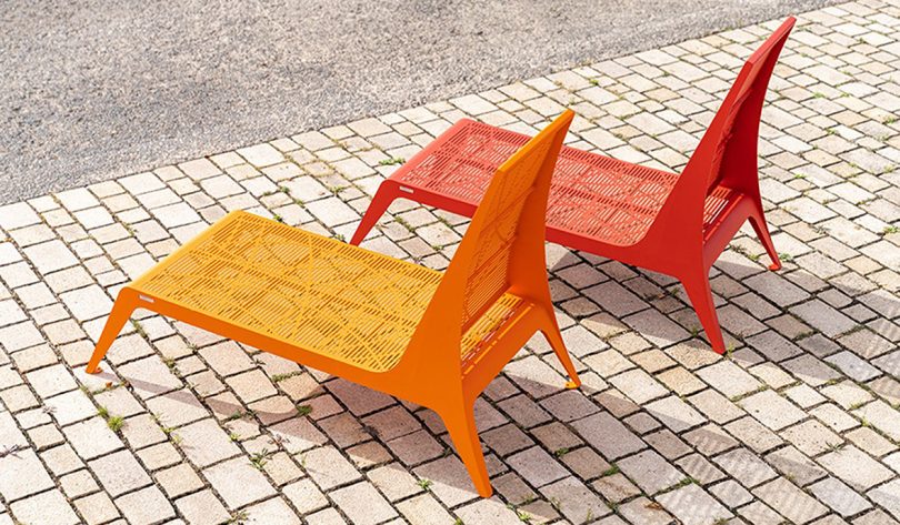 two orange and red low outdoor chairs on a brick surface
