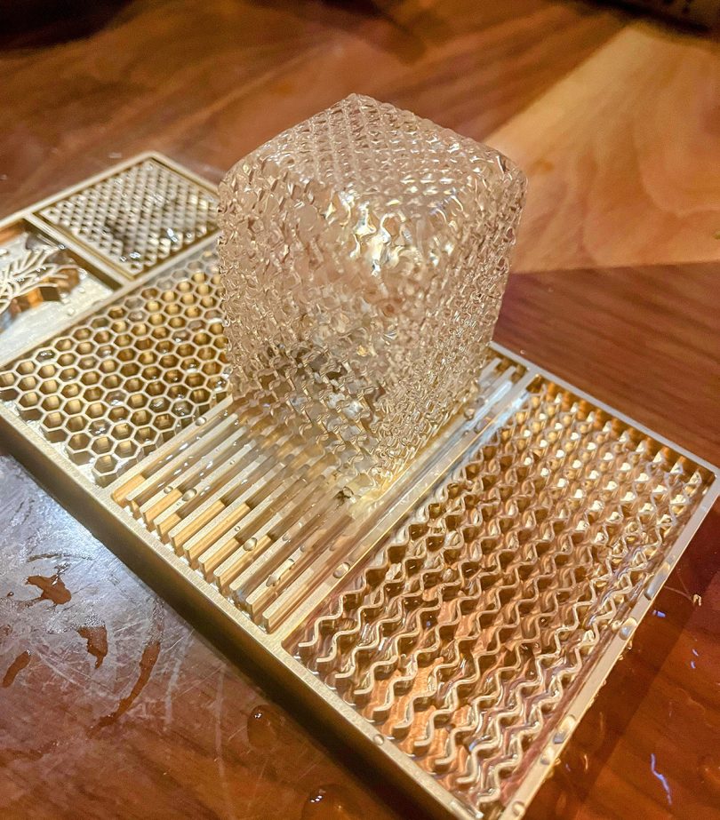 Clear ice cube on a customized ice pattern imprinting plate.