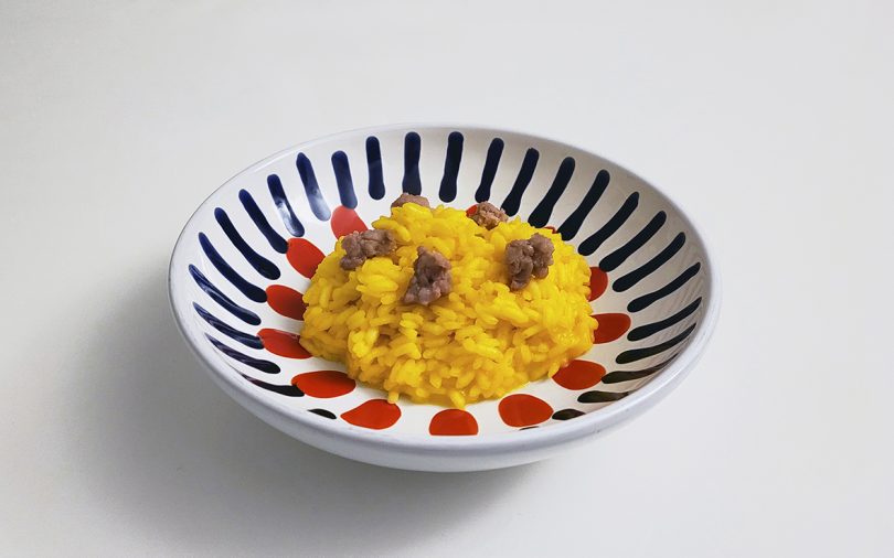 risotto served in a shallow bowl with a red and black design