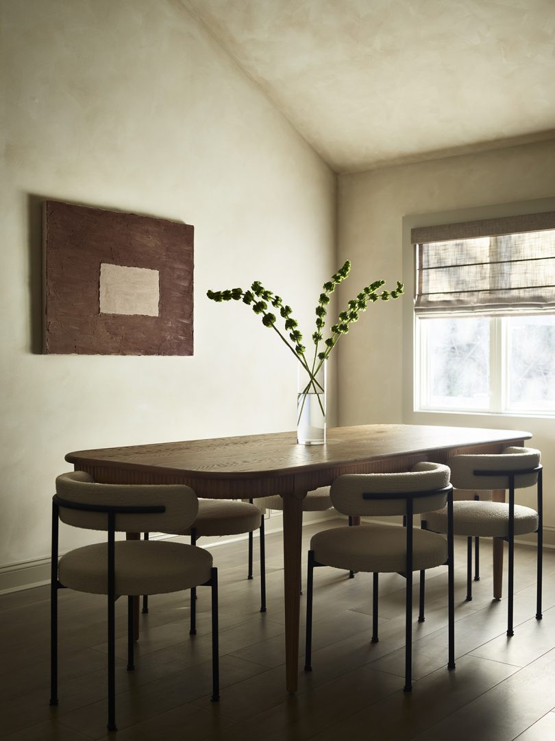 styled dining space with dining table, six chairs, vase, and wall art