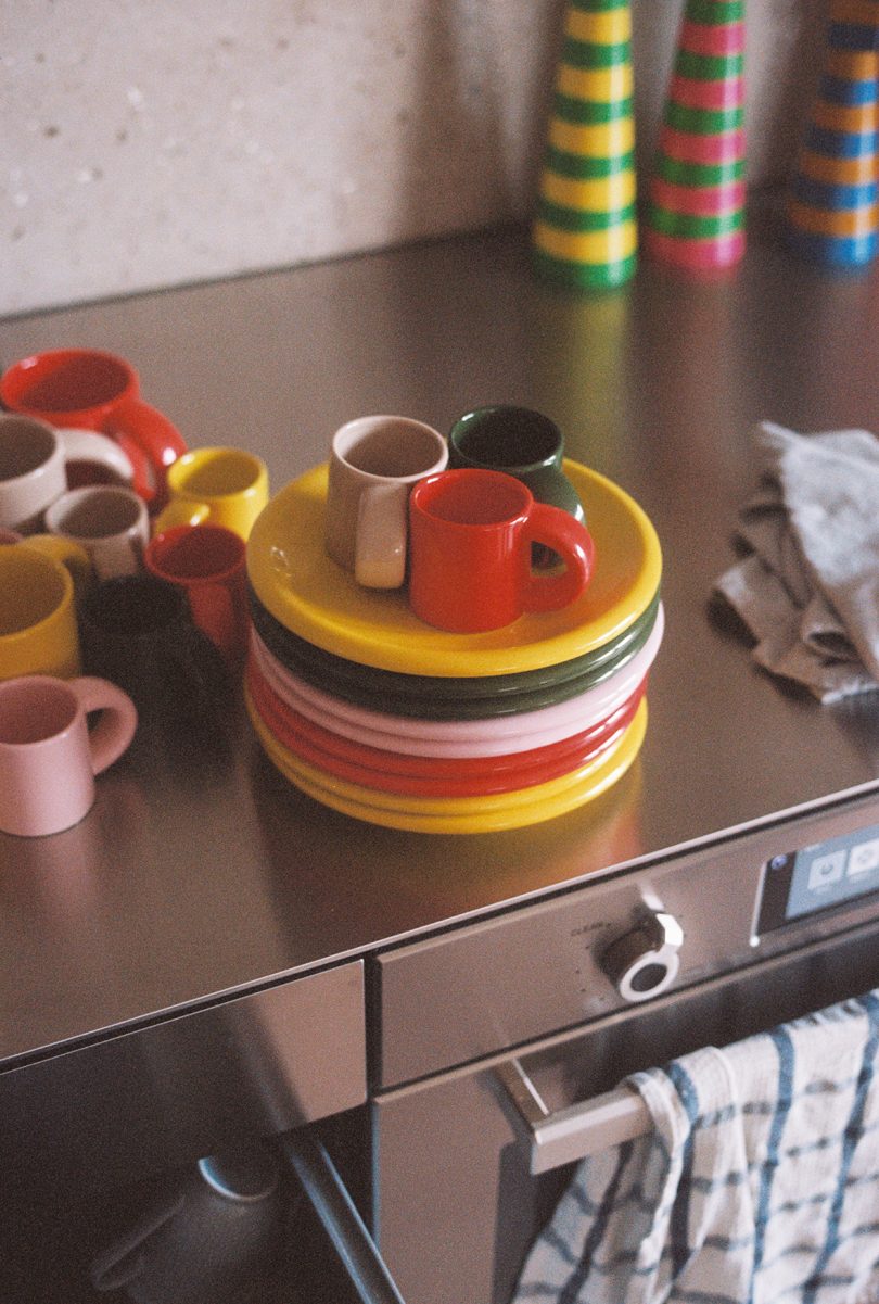 stack of multicolor plates and mugs on a stainless steel kitchen counter