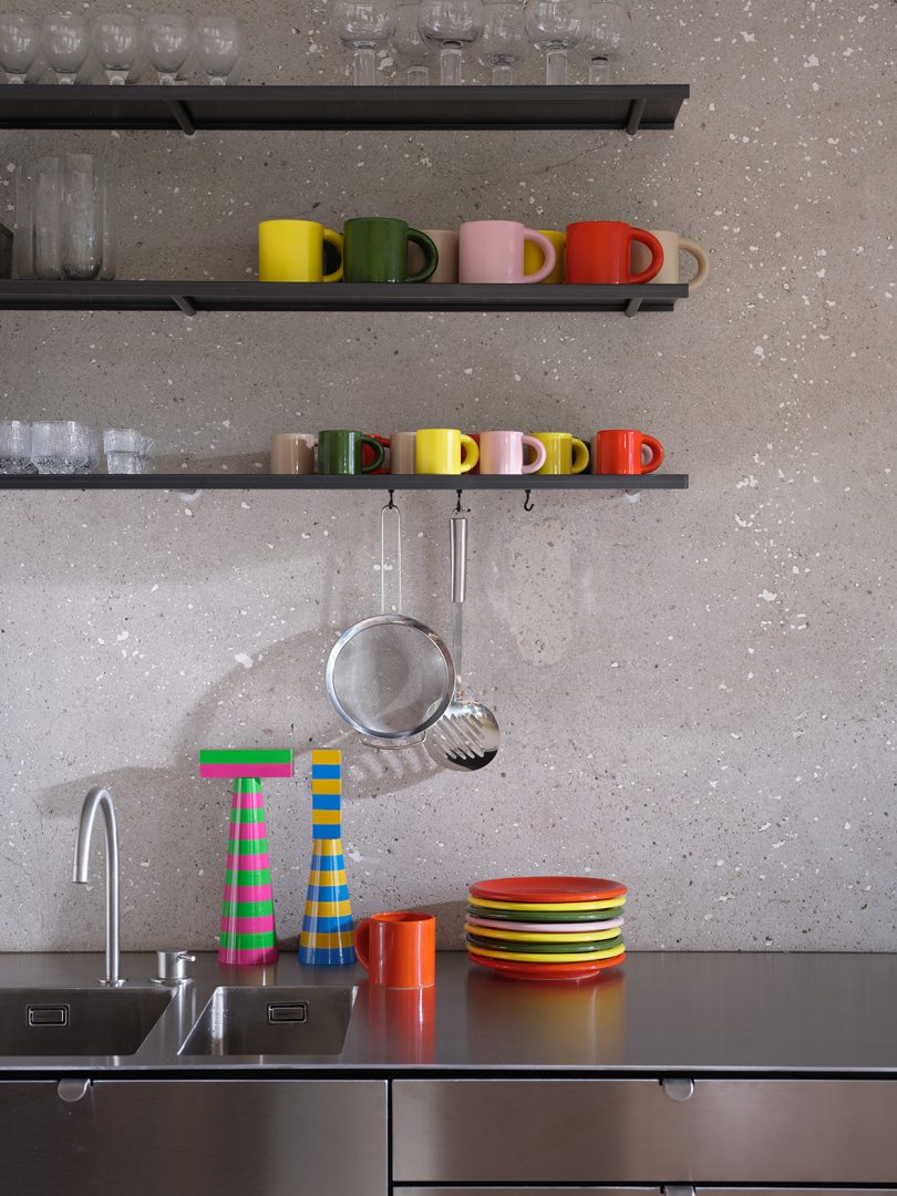 multicolor mugs and plates on a kitchen counter and open shelving