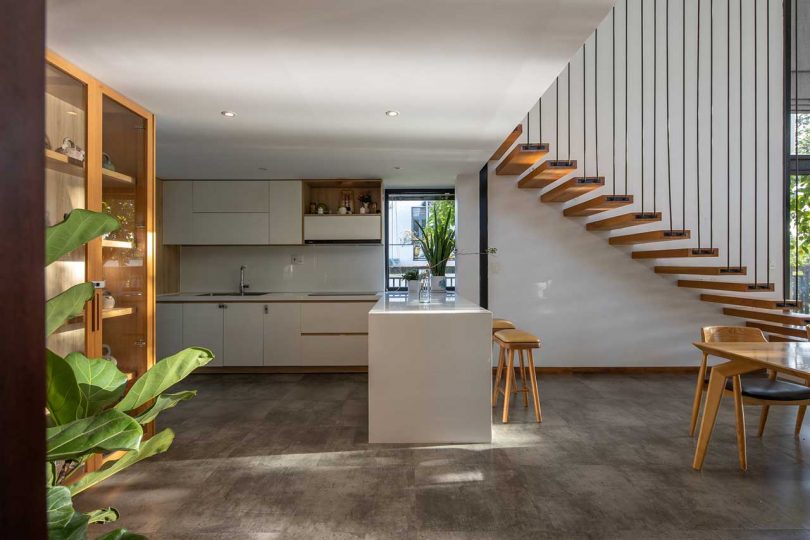 modern house interior with view of white minimalist kitchen under open wood staircase