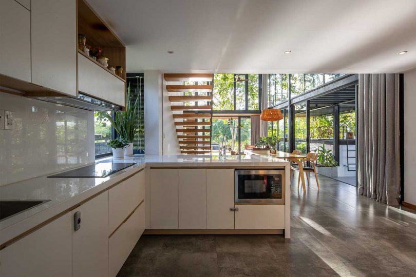 modern house interior with view of white minimalist kitchen under open wood staircase