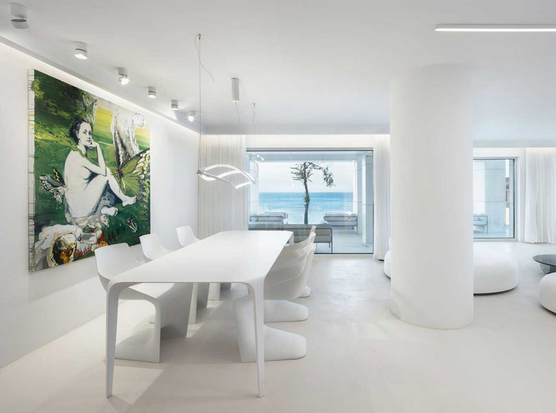 minimalist interior of modern white house with dining room looking out to ocean