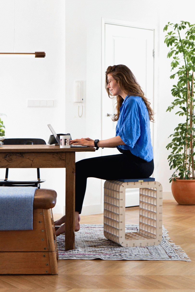 gif of woman sitting on grid stool and then standing at desk