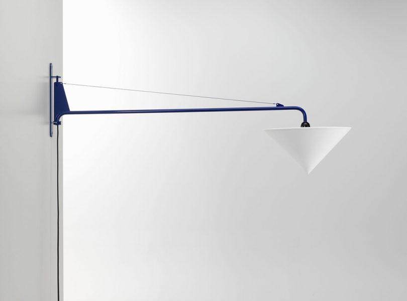 The Potence pivot swing arm wall lamp in blue with white cone shade from side angle view.