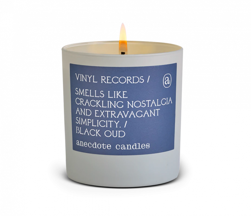grey glass jar candle with a purple label that reads VINYL RECORDS SMELLS LIKE CRACKLING NOSTALGIA AND EXTRAVAGANT SIMPLICITY