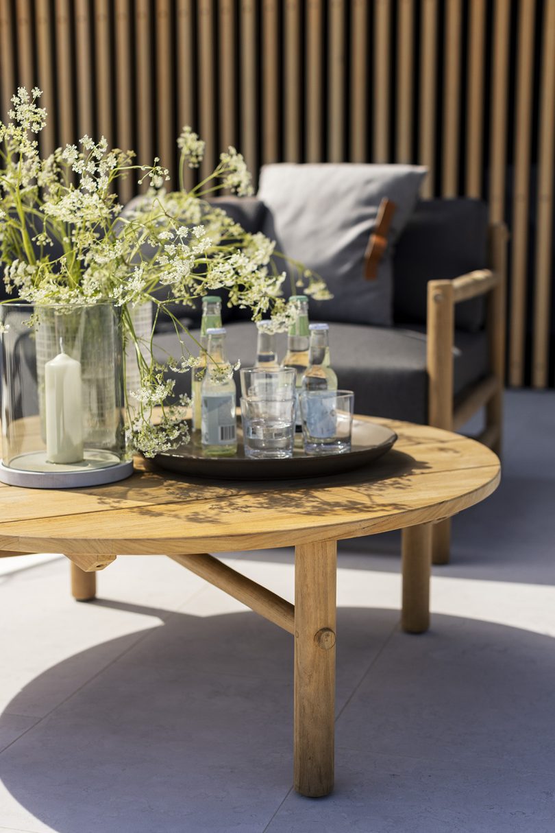 styled round wooden outdoor coffee table with wooden cushioned outdoor armchair