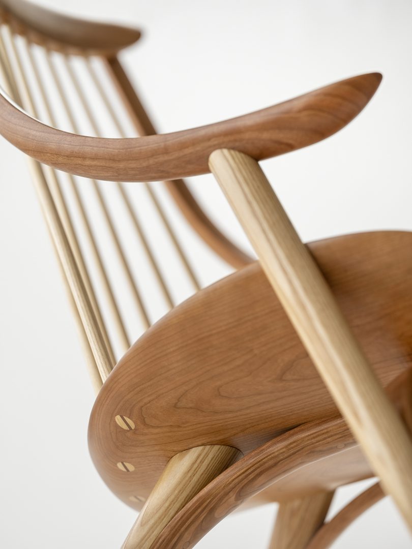 detail of curved wooden armchair with high back on white background