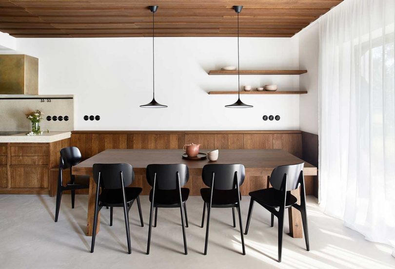 view of modern dining room with wooden details and dark chairs