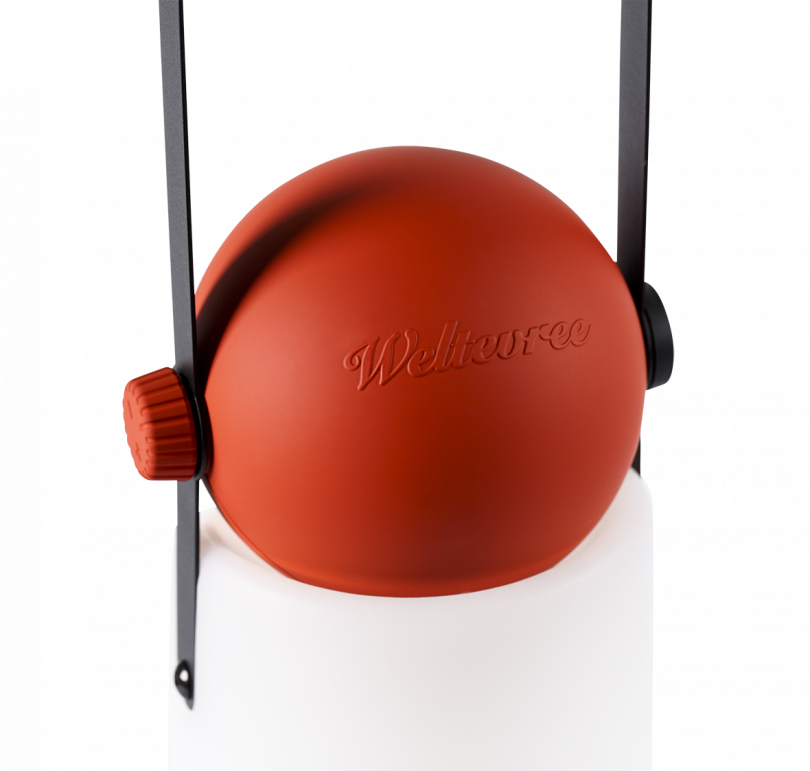 portable lamp with a white base, red top, and black strap handle on a white background
