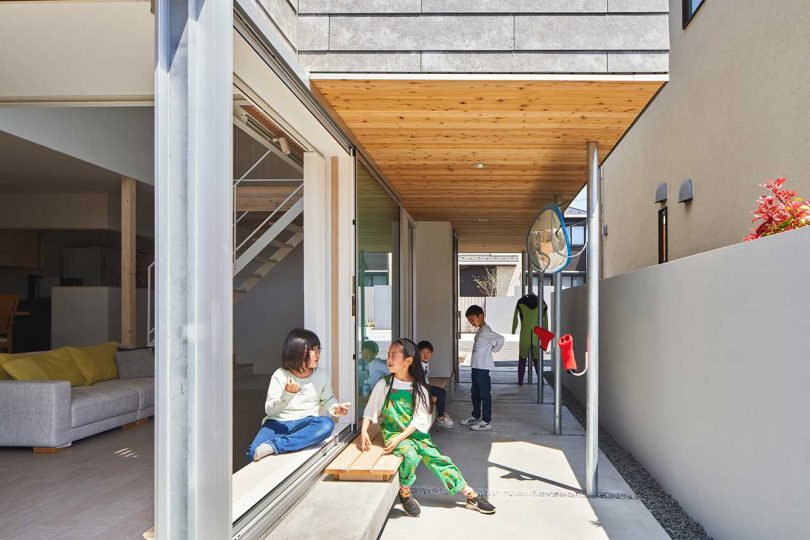 Passageway alongside modern Japanese house with children playing