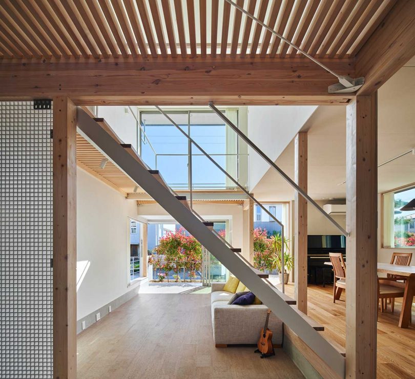 فضای داخلی خانه مدرن ژاپنی که از طریق درگاه به اتاق نشیمن با پله های باز سفید نگاه می کند