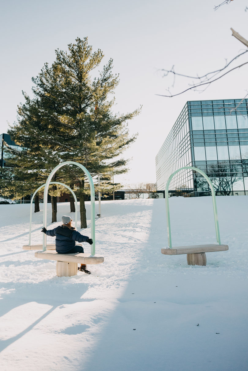 three benches outdoors in the snow with a person sitting on one