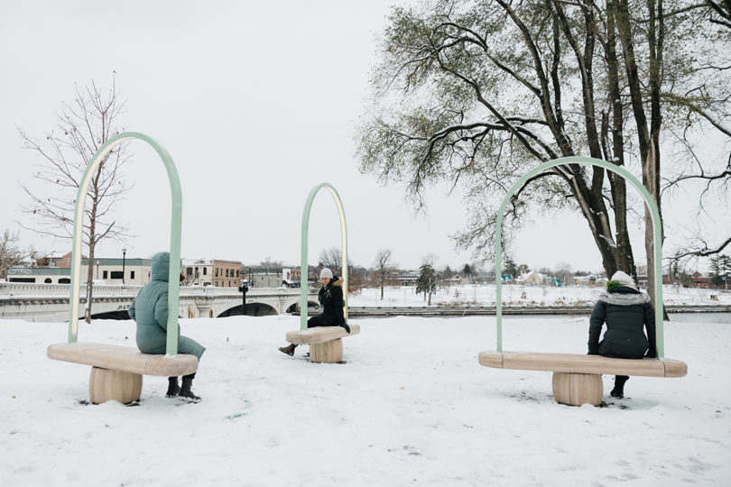 three benches outdoors in the snow with people sitting on them