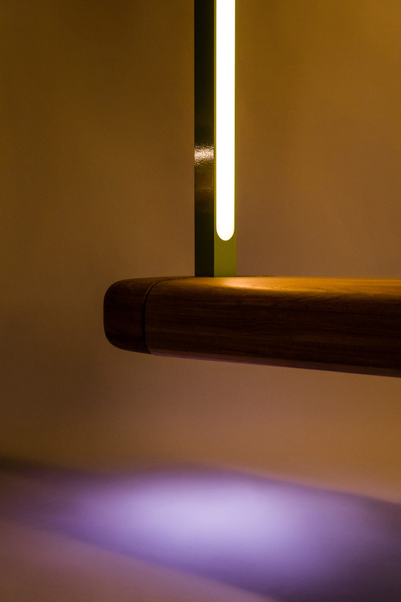 detail of illuminated wooden bench with an overarching metal tube