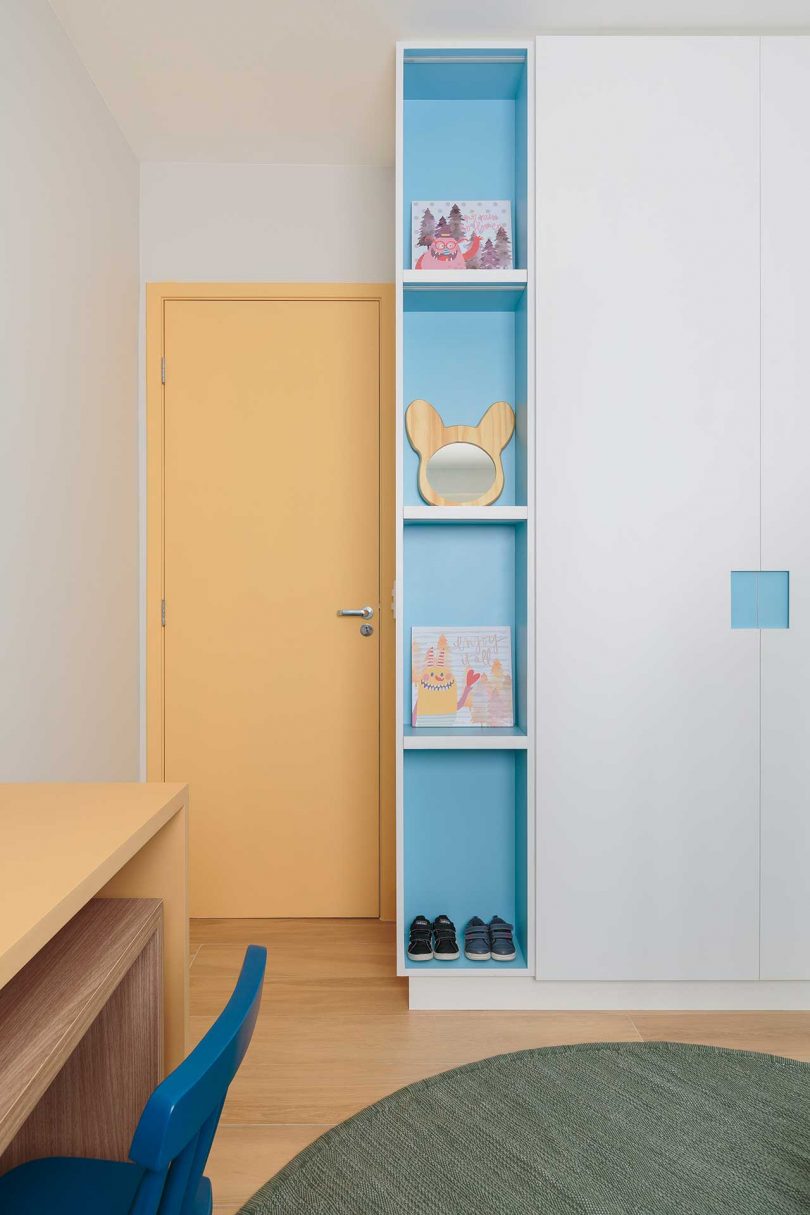 view in kids bedroom of modern apartment with tall blue shelf