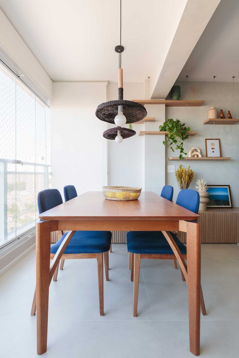 view of open dining room in modern apartment with wood table and blue chairs
