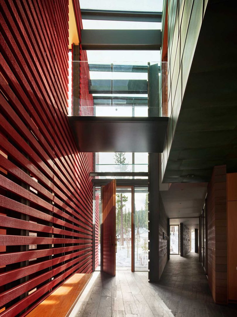 interior shot of long hallway of modern home with large red-slatted wall and skylights