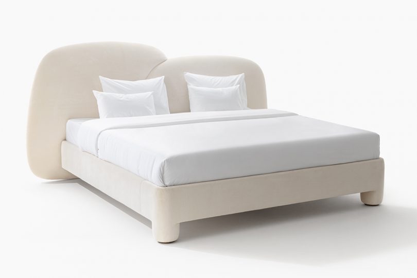 cream color upholstered bed with abstract headboard and white bedding