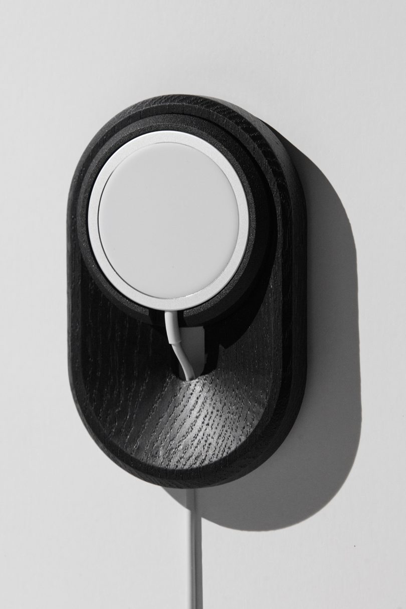 a black wood vertical iPhone charging dock hanging on a wall