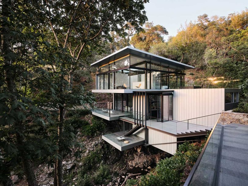 angled view of multi story modern house built over river between two hills