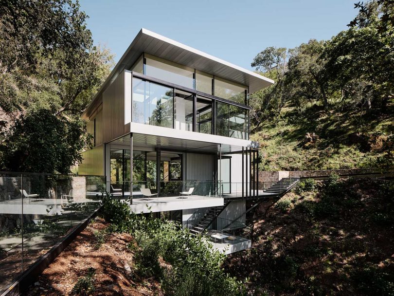 multi story modern house built over river between two hills