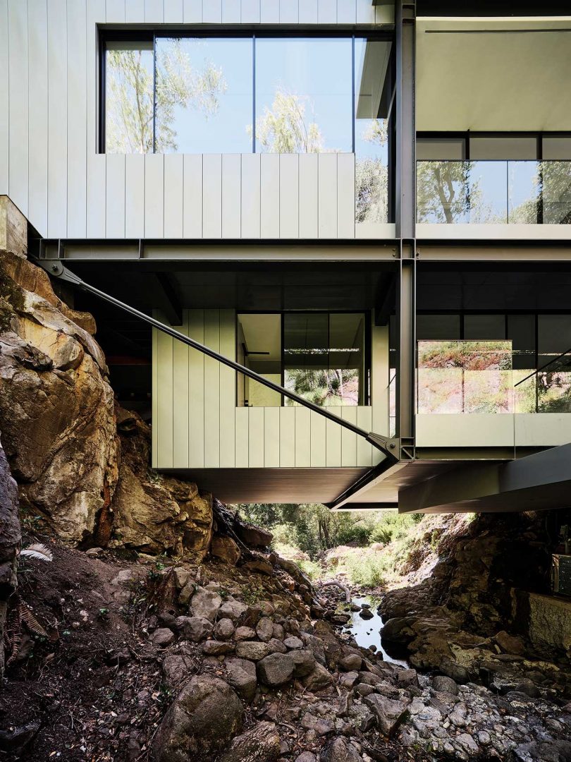 closeup of multi story modern house built over river between two hills