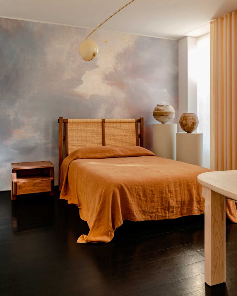 styled interior space with bed, bedside table, and sculptural objects