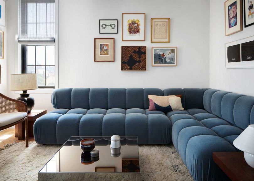 interior of modern living space with tufted blue section sofa and gallery wall of art