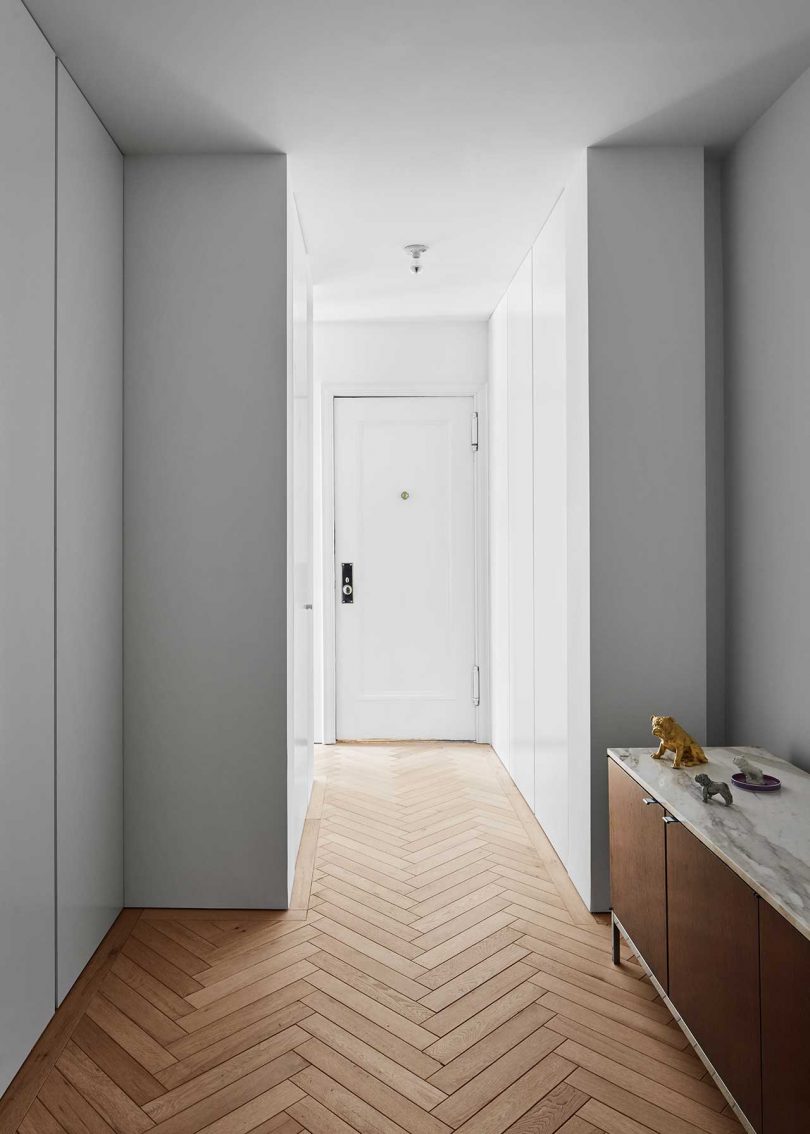view down white hallway with herringbone wood floors