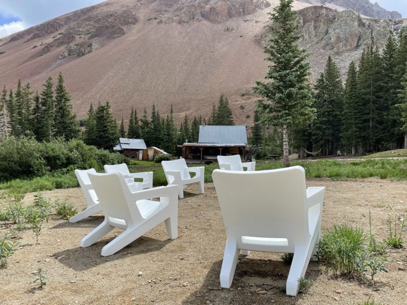two white outdoor armchairs facing a campsite