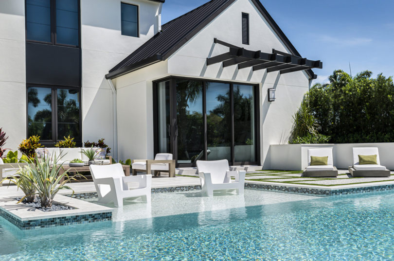 two white outdoor armchairs in the shallow end of a modern pool