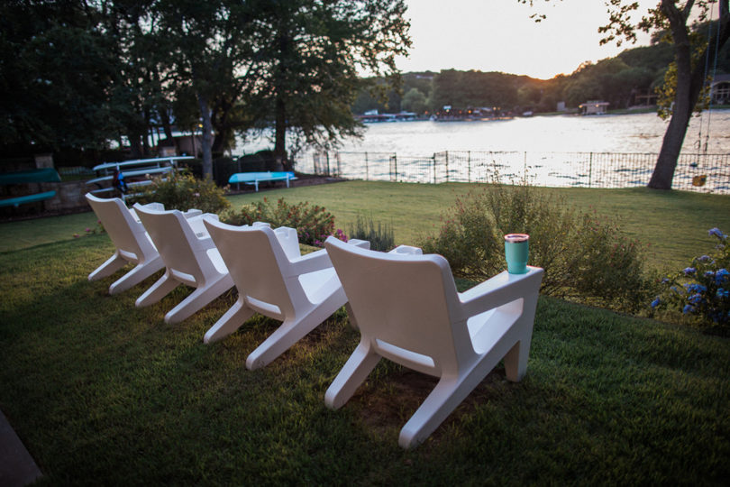 two white outdoor armchairs facing a lake